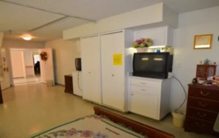 A living room with a television on a cabinet, surrounded by white furniture and decor.