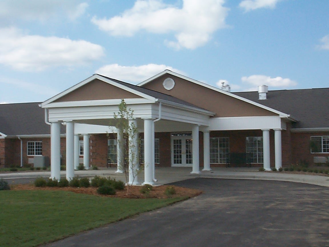 A building with a prominent entrance featuring columns under a partly cloudy sky.