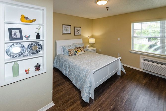 A cozy bedroom with a neatly made bed, decorated with pillows and artwork on the walls.