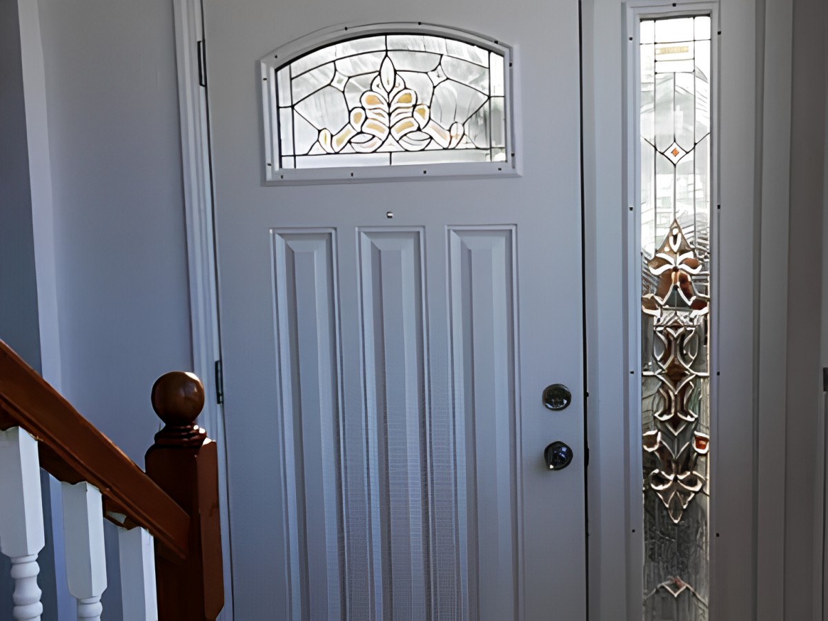 A white front door with ornate stained glass panels, viewed from the interior.