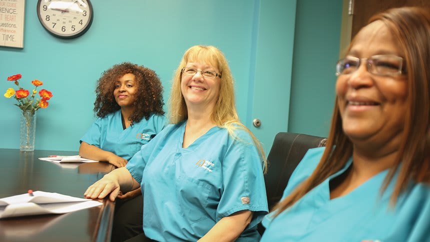 A group of women in uniform smiling during a meeting.