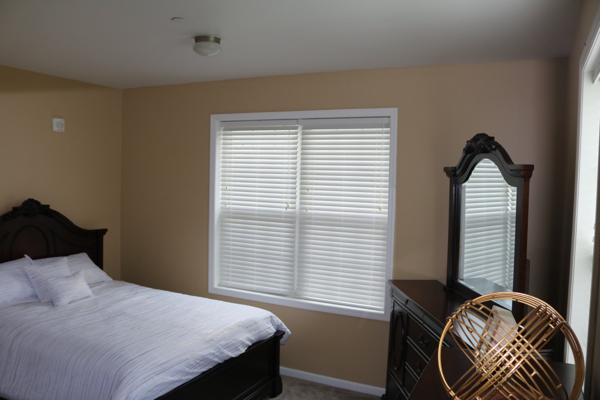A cozy bedroom with a bed, dresser, and window with blinds.