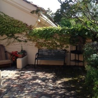 A serene garden patio with a bench and ivy-covered walls.