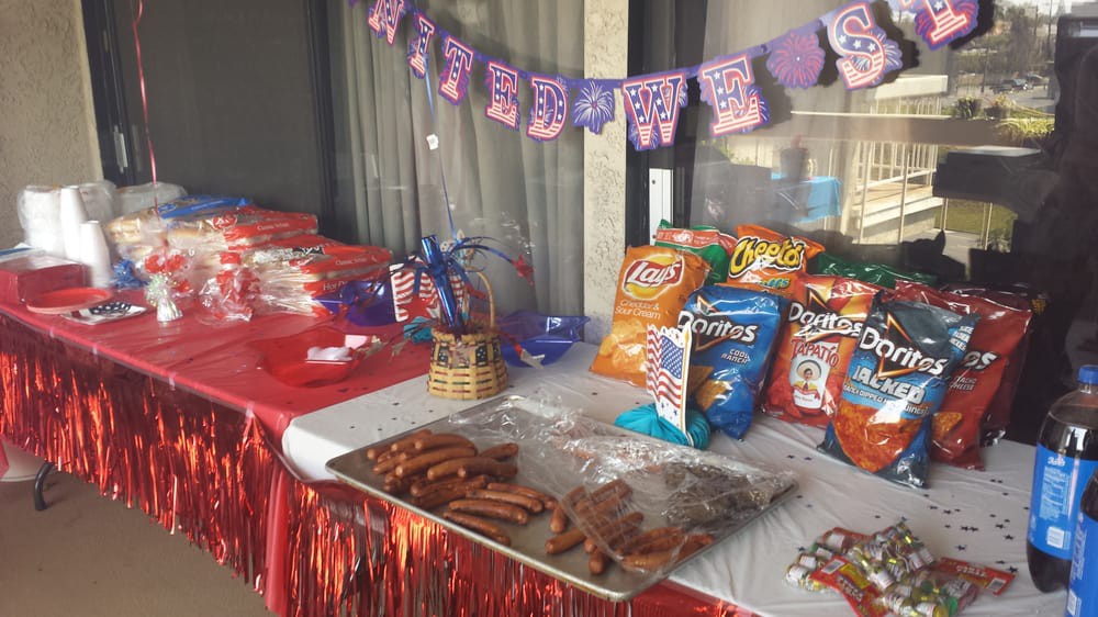 A festive table setup with a variety of snacks and sausages, adorned with a colorful birthday banner.