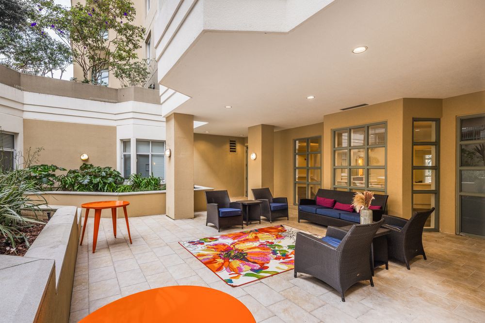 A modern indoor seating area with stylish furniture, colorful rug, and decorative plants.