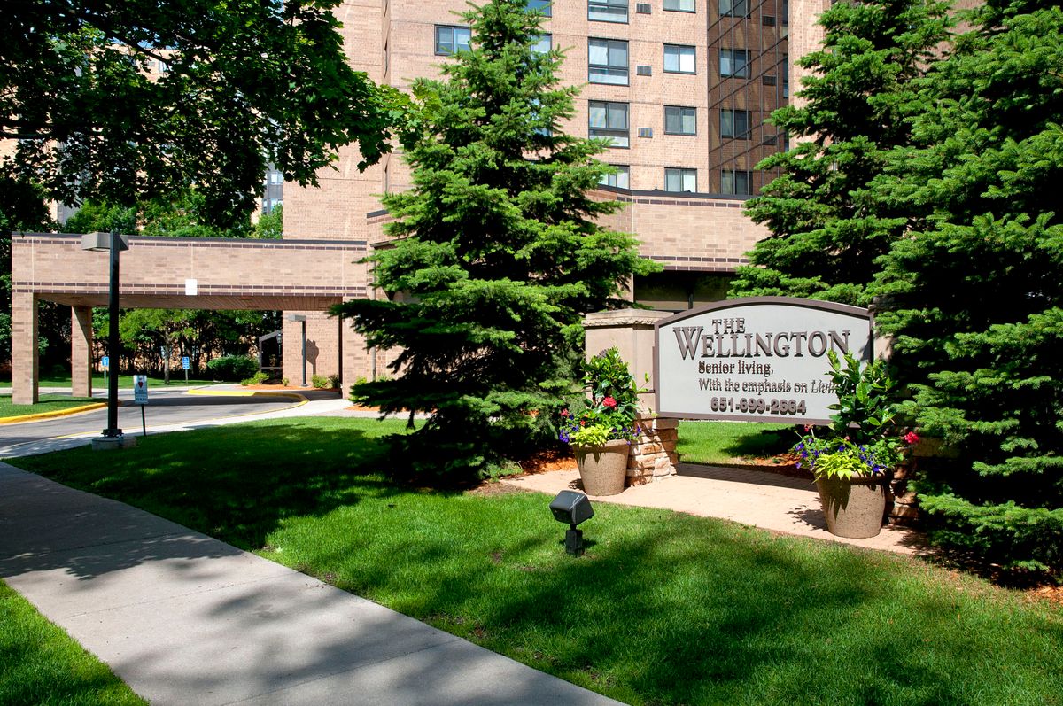 Entrance of The Wellington apartment building with well-maintained landscaping.