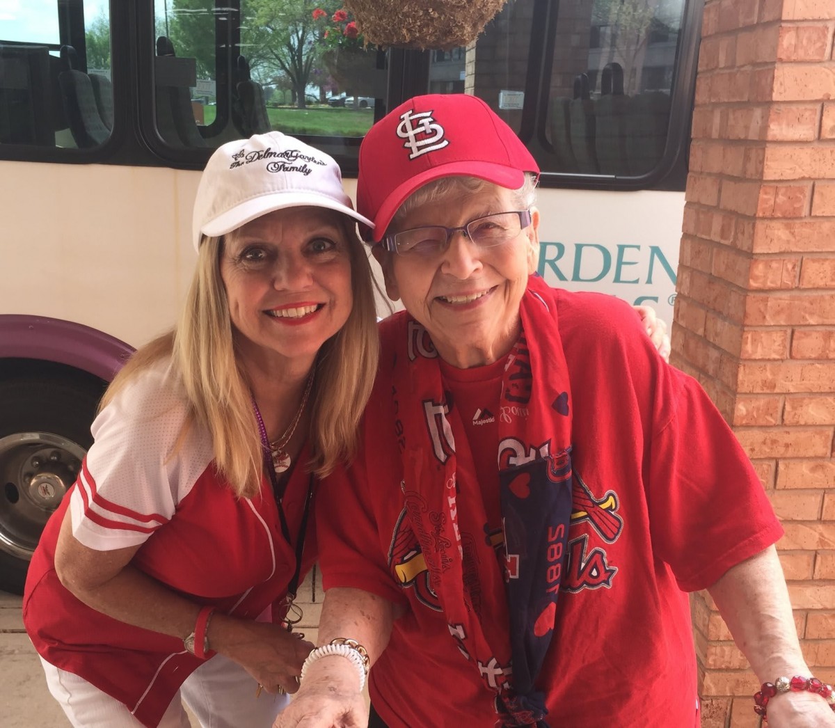 Two women smiling and posing together, wearing hats and red clothing.