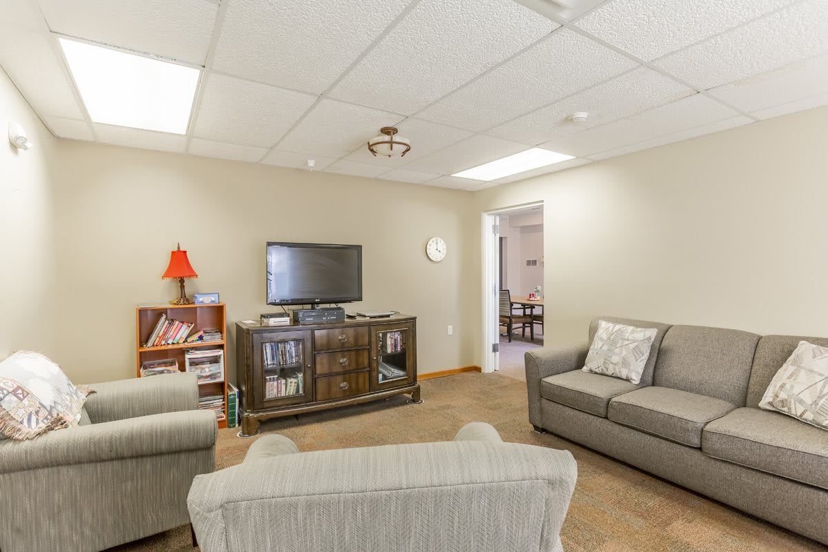 A cozy living room with a television, couches, and a bookshelf.