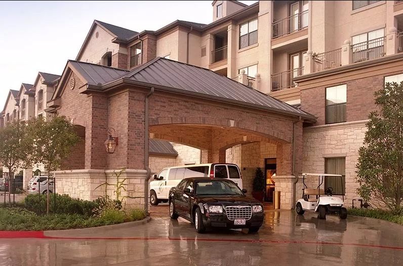 Hotel entrance with parked vehicles and a covered driveway.