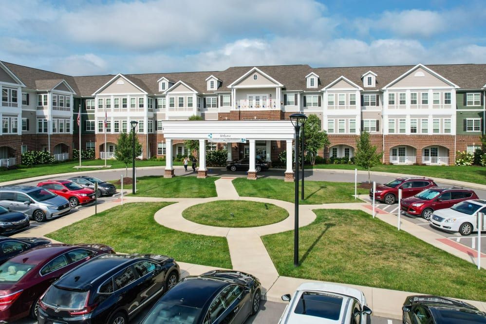 A modern residential building with a parking lot and landscaped entrance.