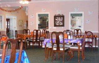 A cozy dining area with multiple tables and chairs, featuring a warm and inviting decor.