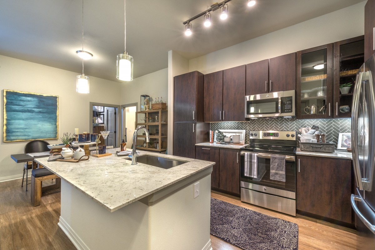 A modern kitchen interior featuring dark cabinets and stainless steel appliances.