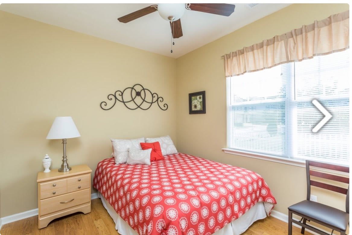 A cozy bedroom with a red polka dot bedspread, complete with a wooden nightstand and decorative wall art.
