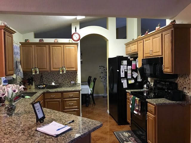 A cozy kitchen with wooden cabinets, a black refrigerator, and a granite countertop.