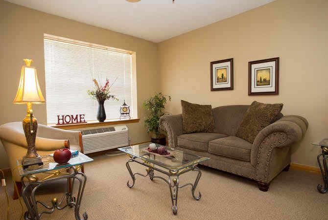 A cozy living room with a large sofa, glass coffee table, and decorative elements.