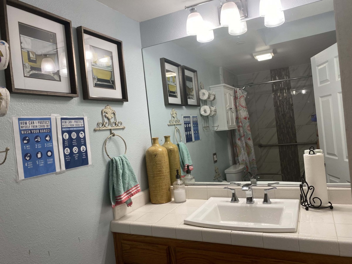 A well-decorated bathroom featuring a large mirror, a sink with modern fixtures, and framed artwork on the wall.