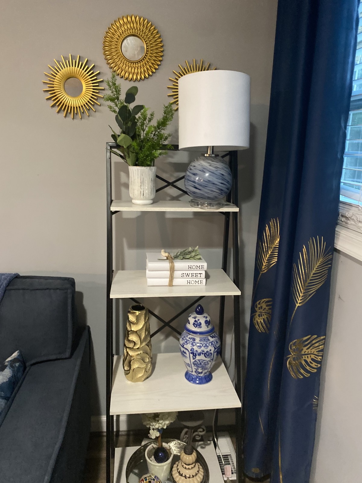 A stylish living room shelf with a lamp, plant, books, and decorative vases.