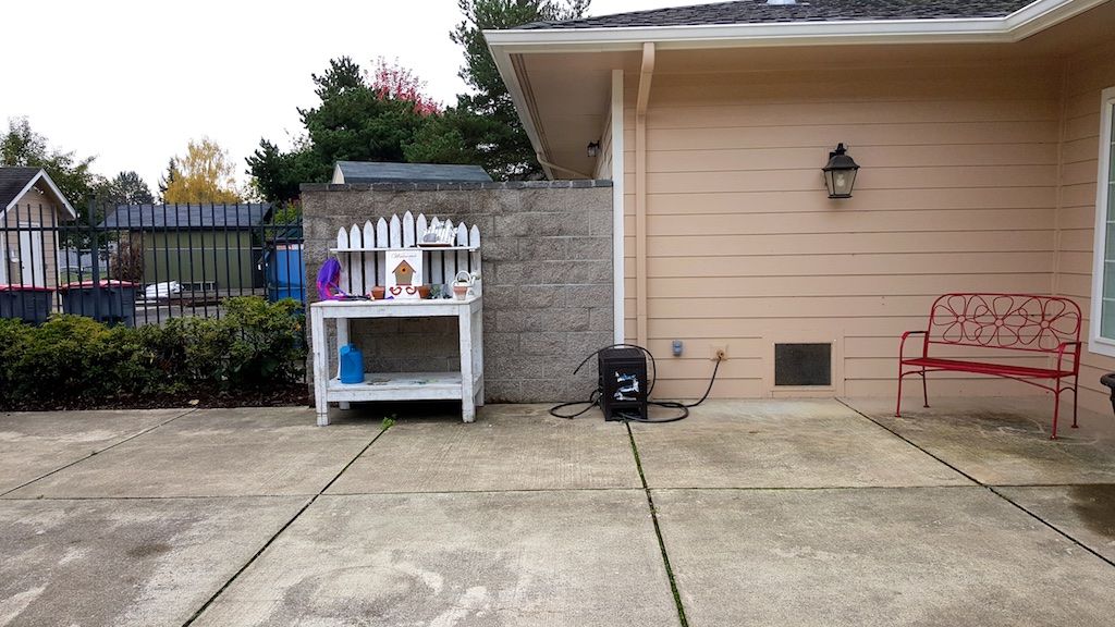 An outdoor space featuring a pressure washer and a small table against the house.