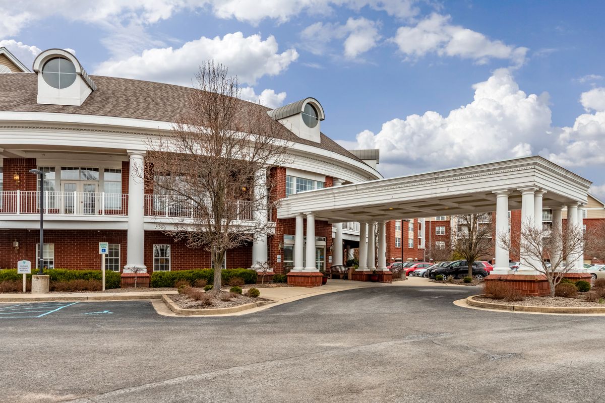 A large hotel building with a circular driveway and prominent entrance against a partly cloudy sky.