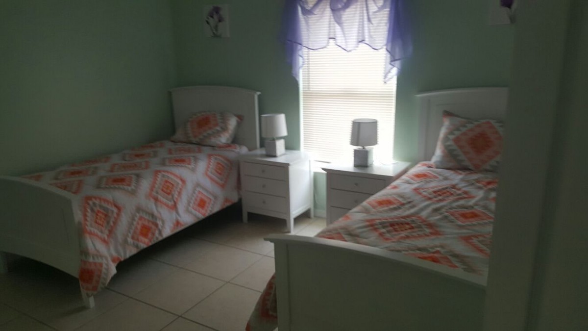 A cozy bedroom with twin beds, a nightstand, and a window with curtains.