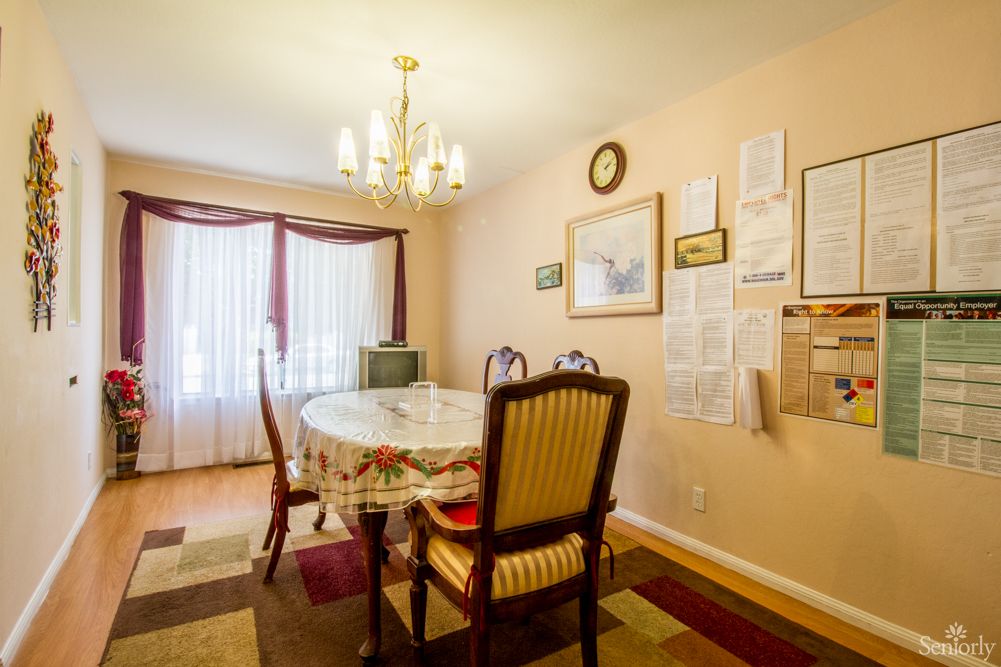 A cozy dining room with a table set, chandelier, and wall decorations.