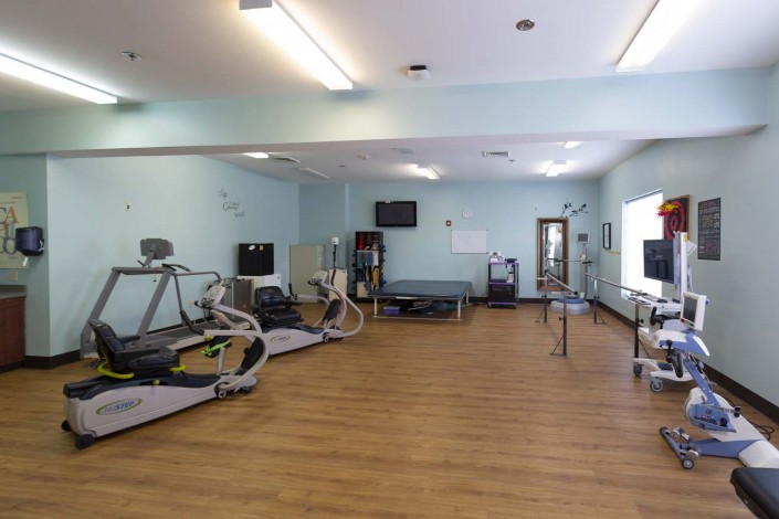 A spacious rehabilitation gym equipped with treadmills and other exercise machines.