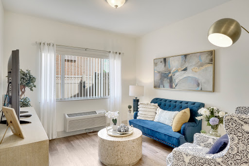 A cozy and modern living room featuring a blue sofa, elegant coffee table, and ample natural light.