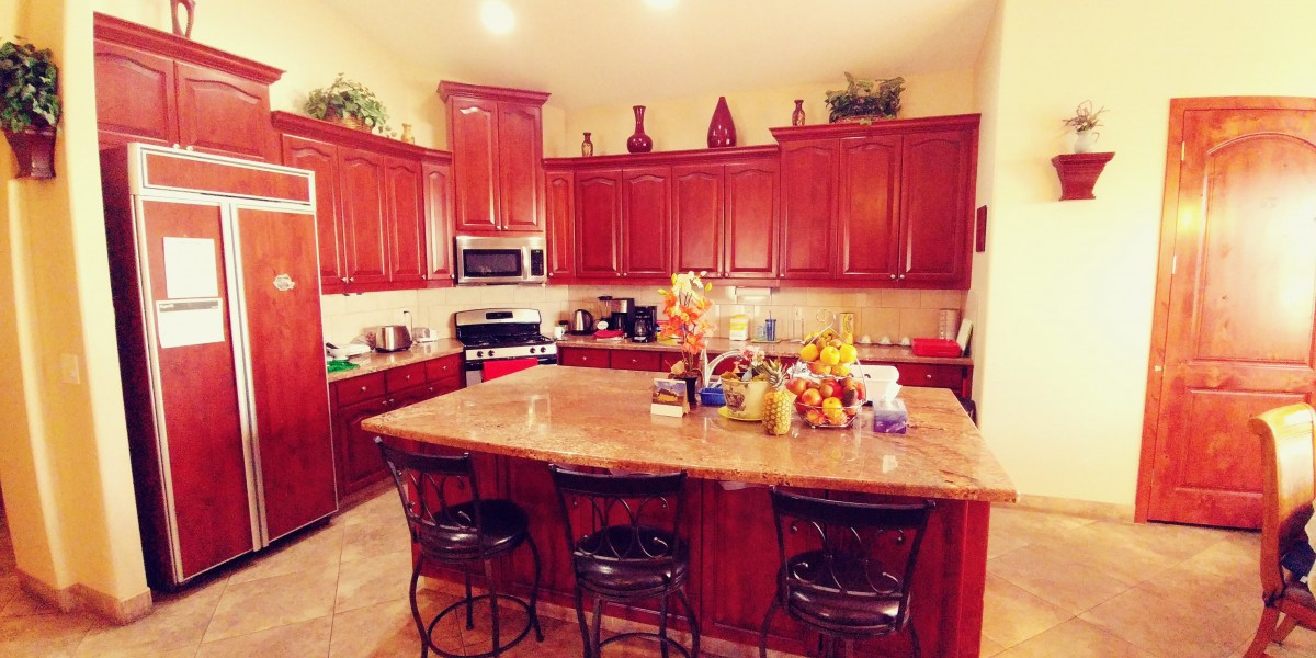 A spacious kitchen with wooden cabinets and a central island adorned with fruit and decor.