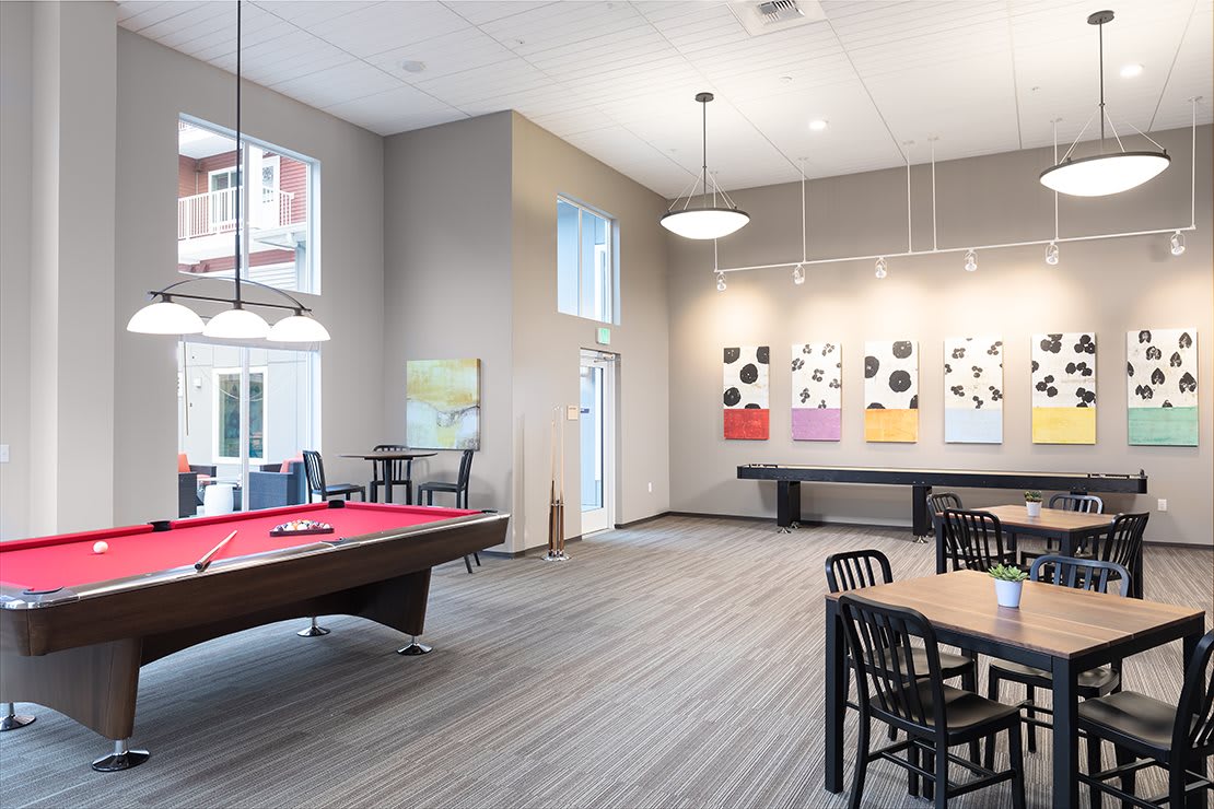A modern game room featuring a billiard table, contemporary artwork, and ample natural light.