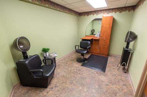 A cozy and well-lit salon area with black chairs and a wooden cabinet.