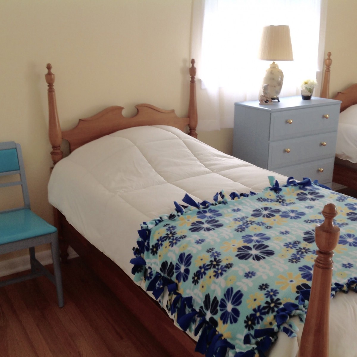A cozy bedroom with twin beds adorned with floral quilts, accompanied by a nightstand and lamp.