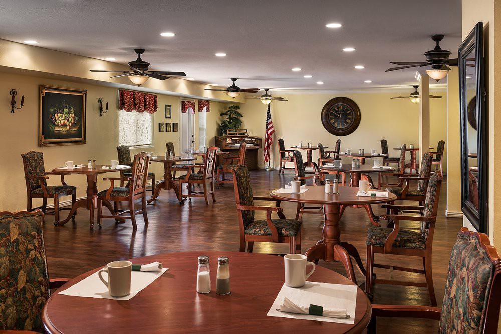 An empty dining area with neatly arranged wooden tables and chairs, softly lit and decorated with simple interior elements.