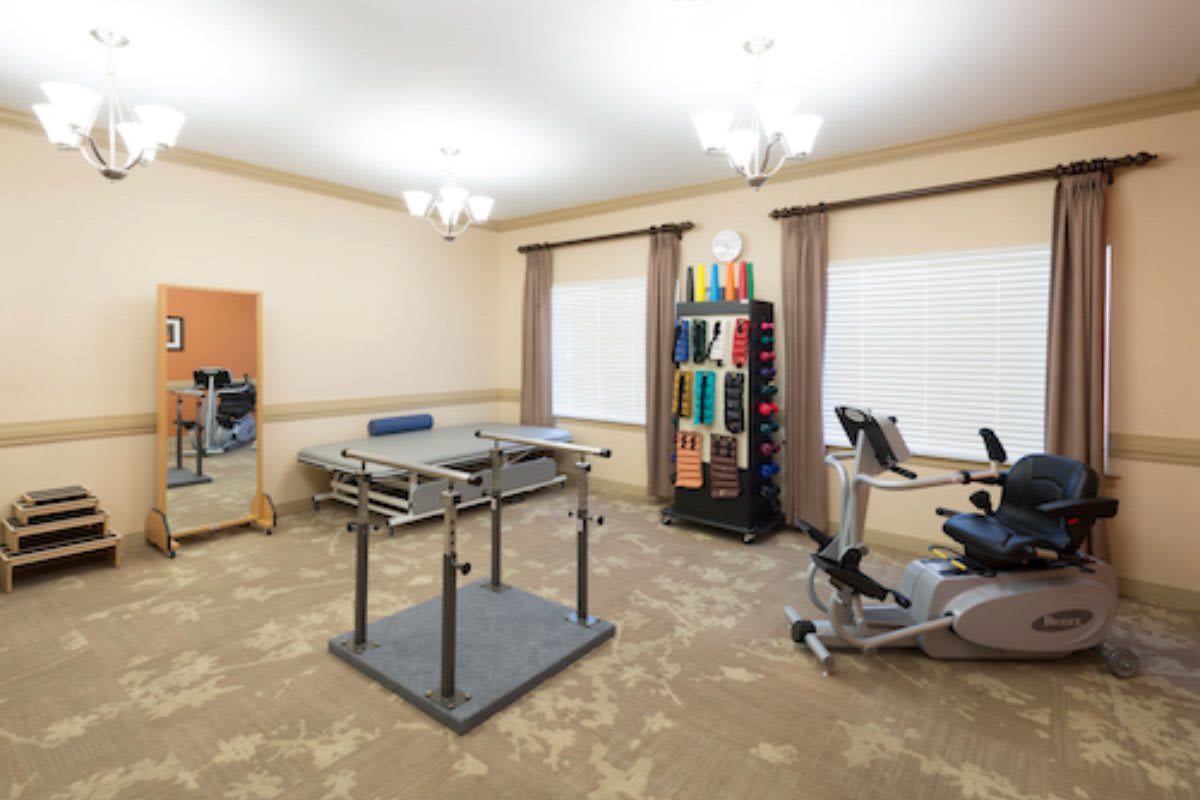 A rehabilitation room equipped with various therapy tools and exercise equipment, including a therapy table and exercise bikes.