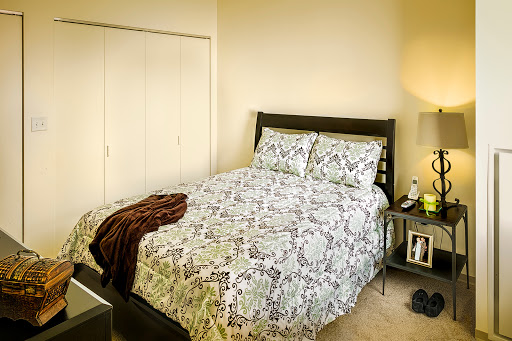 A cozy bedroom featuring a neatly made bed with patterned bedding and a bedside lamp.