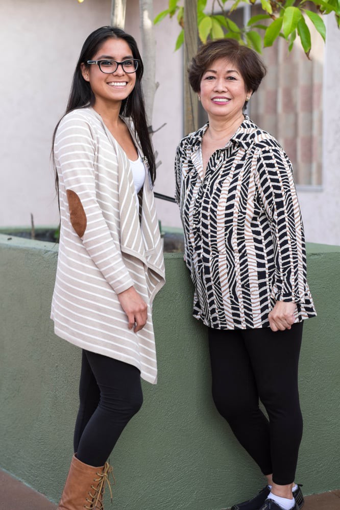 Two women smiling in casual clothing outdoors.