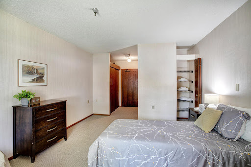 A cozy and well-lit bedroom featuring a neatly made bed, dresser, and access to a closet.