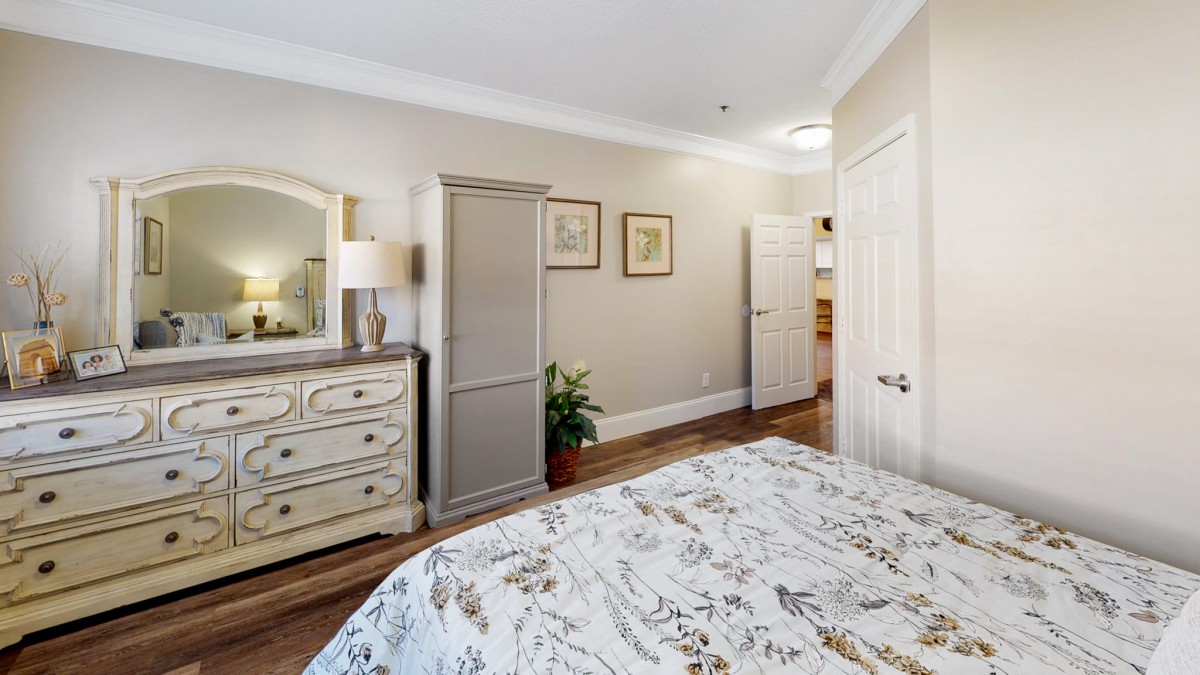 A cozy bedroom with a floral bedspread, dresser, wardrobe, and decorative elements.