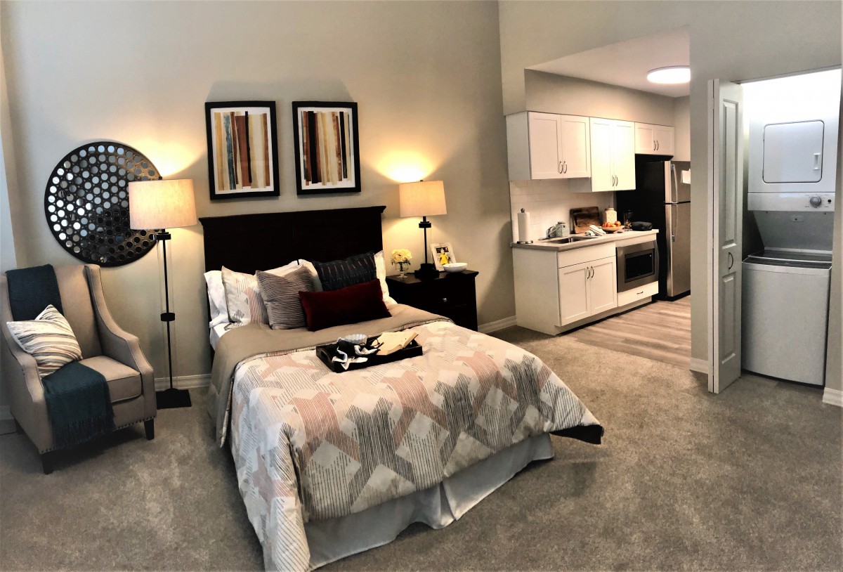 A cozy studio apartment with a modern bedroom and a kitchenette.
