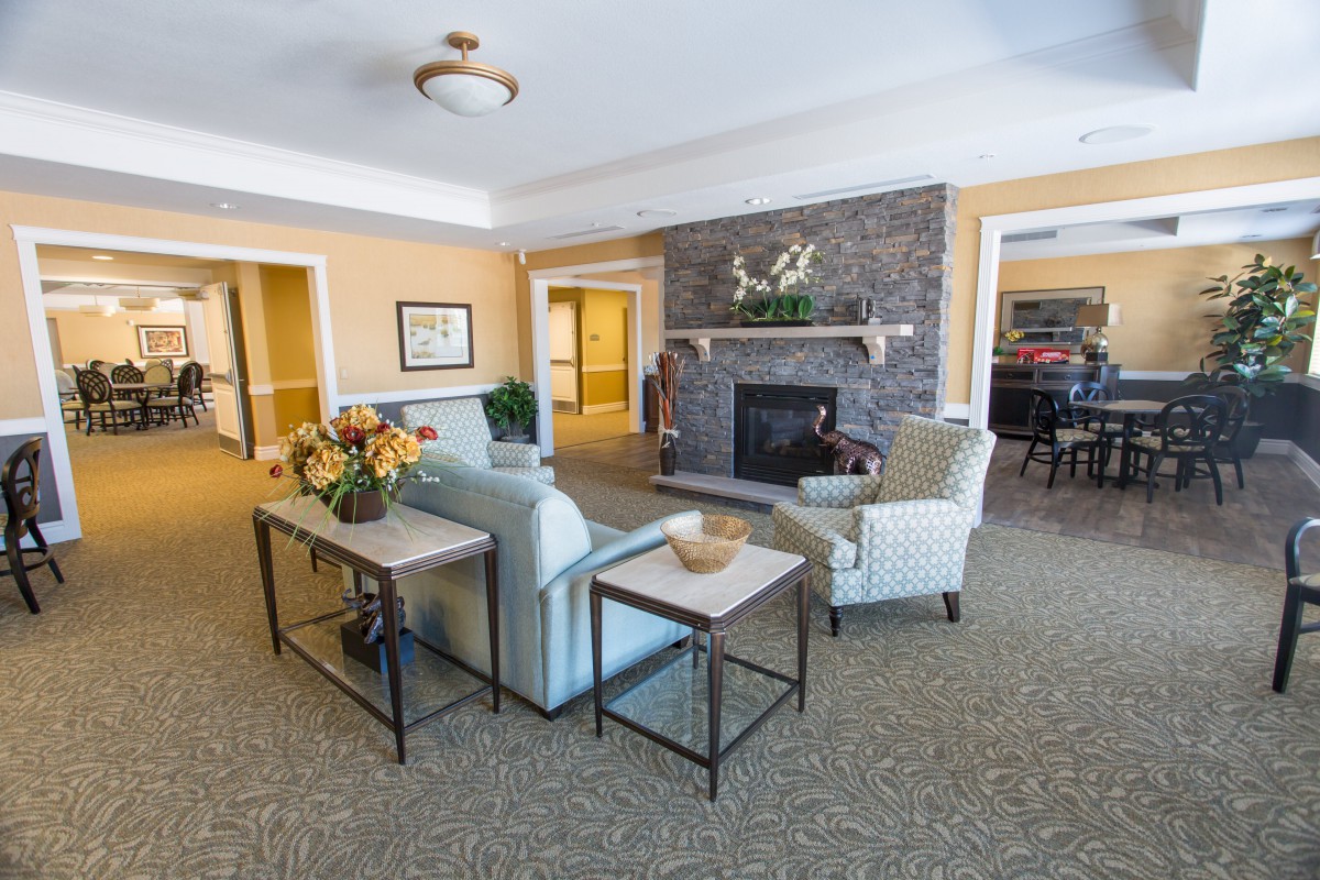 A cozy living room with a modern fireplace, comfortable sofa, and armchairs.