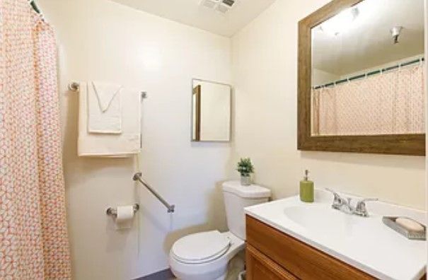 A simple and clean bathroom with a toilet, sink, and mirror.