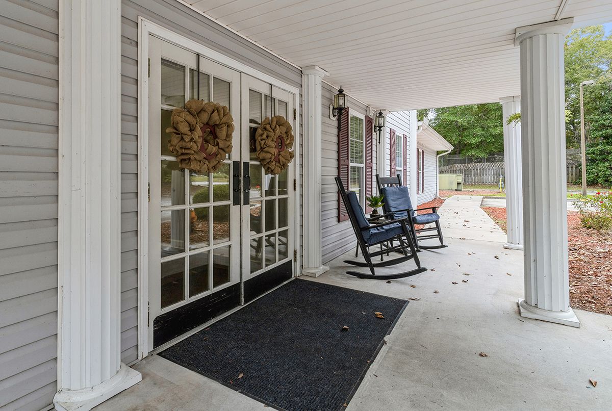 A cozy front porch with rocking chairs and decorative wreaths on double doors.