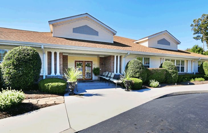 A well-maintained building entrance with columns and lush greenery.