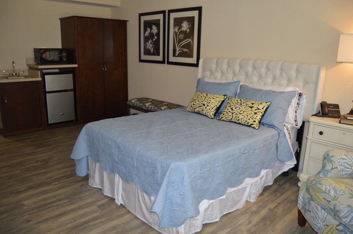 A cozy bedroom featuring a bed with blue bedding and decorative pillows, complemented by framed art on the wall.