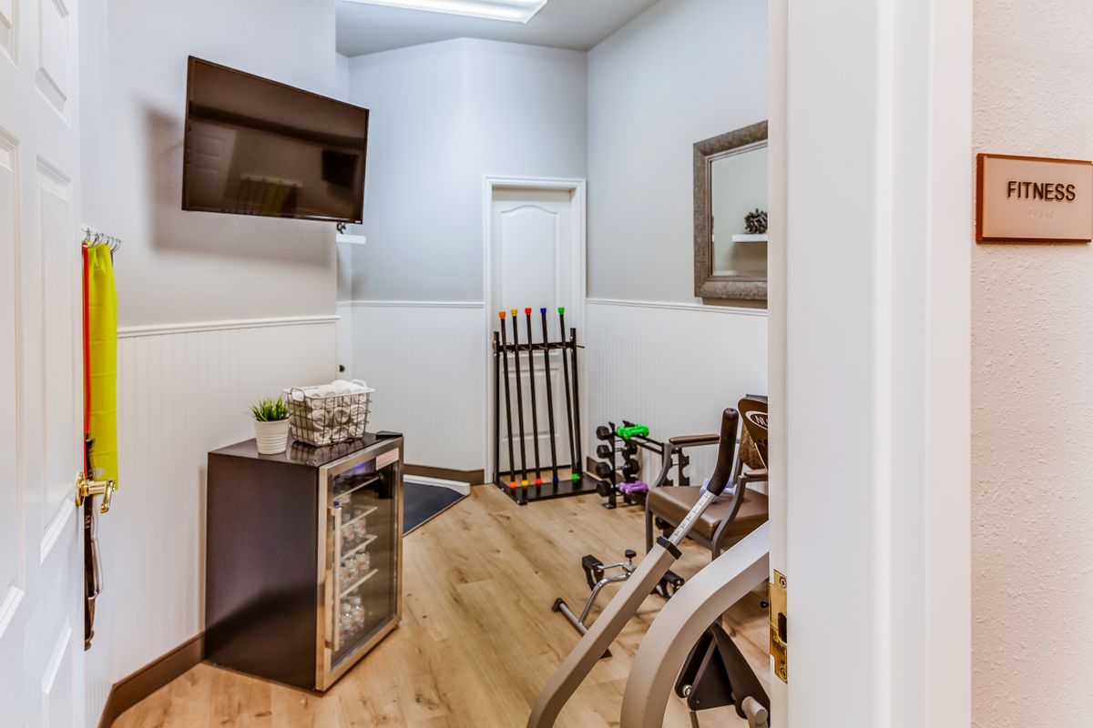 A modern waiting room with a television, stylish furniture, and wooden flooring.