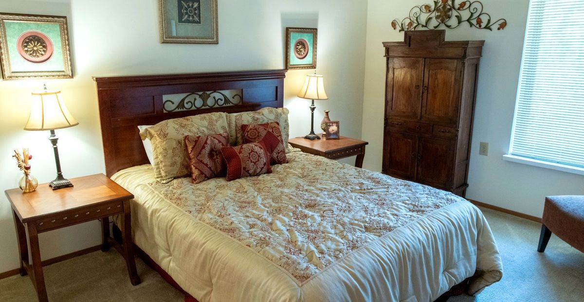 A cozy bedroom with a neatly made bed, decorative pillows, and warm lighting.