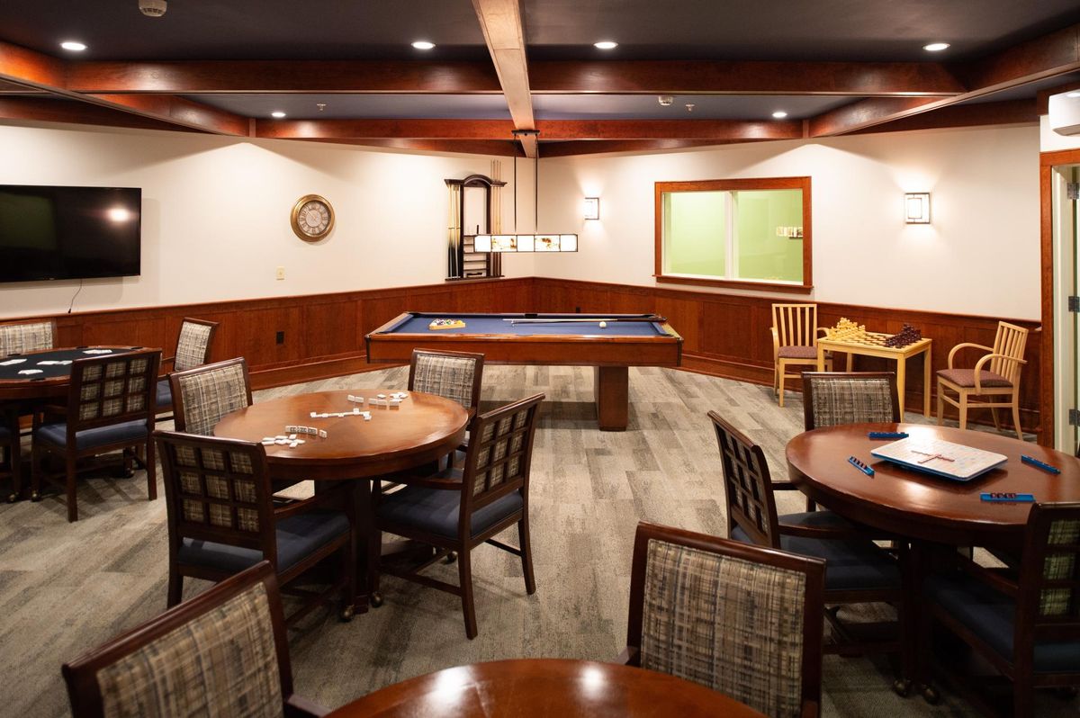 A cozy game room featuring a pool table and multiple tables with chairs for socializing.