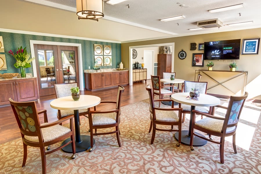 A cozy dining area with multiple tables and chairs, wood flooring, and tasteful decor.