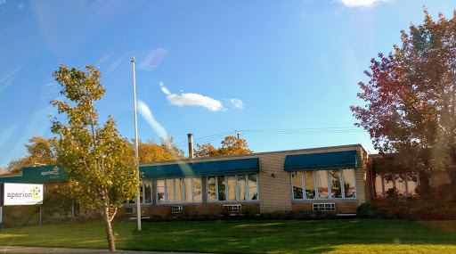 A sunny day showcasing a building with green awnings and a flagpole in front.