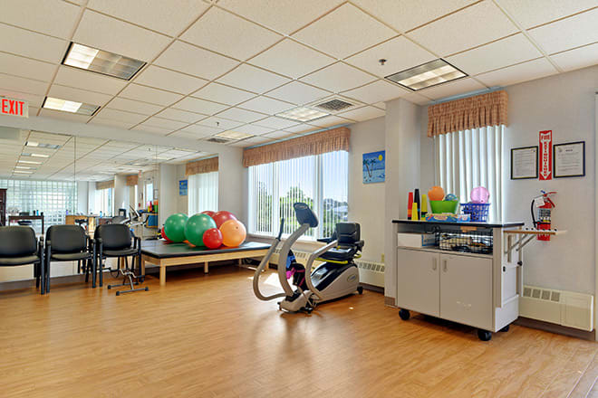 A well-equipped physical therapy room featuring a stationary bike and various therapy balls.
