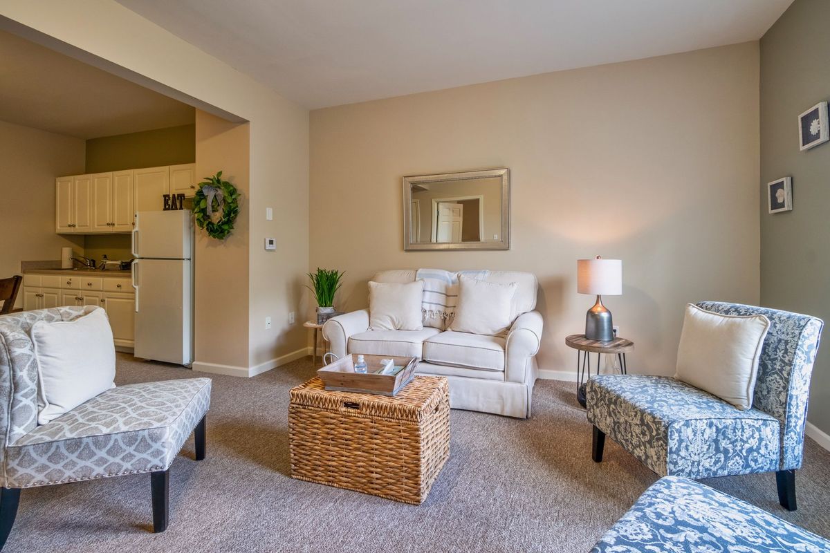 A cozy living room with a comfortable sofa, armchairs, and a wicker table.